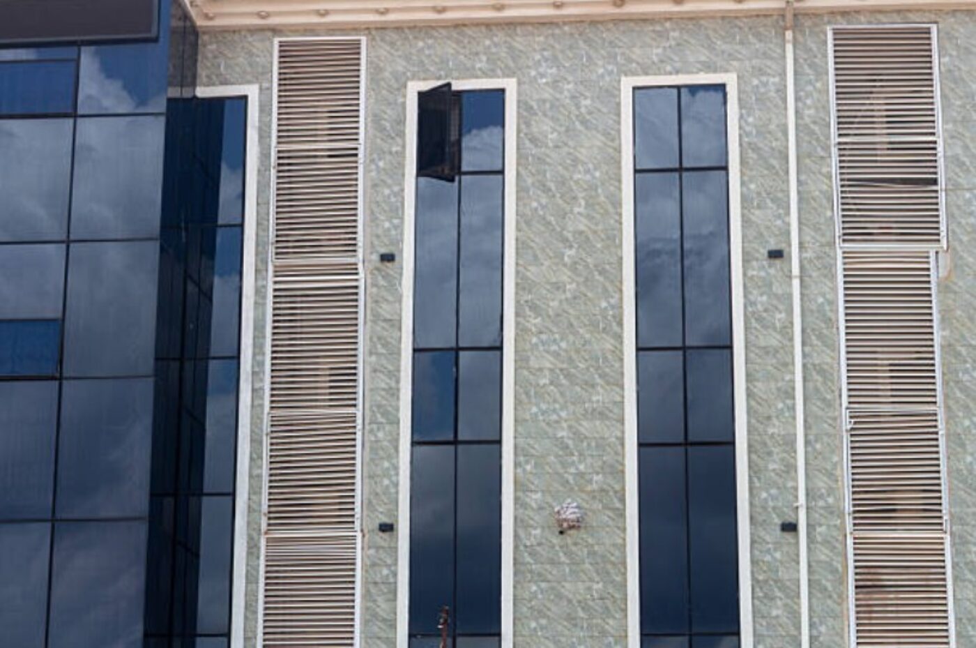 Vertical aluminum louvers installed on a modern building facade alongside tall glass windows.