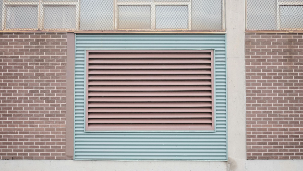 Building exterior with a large ventilation grate set into a brick wall.