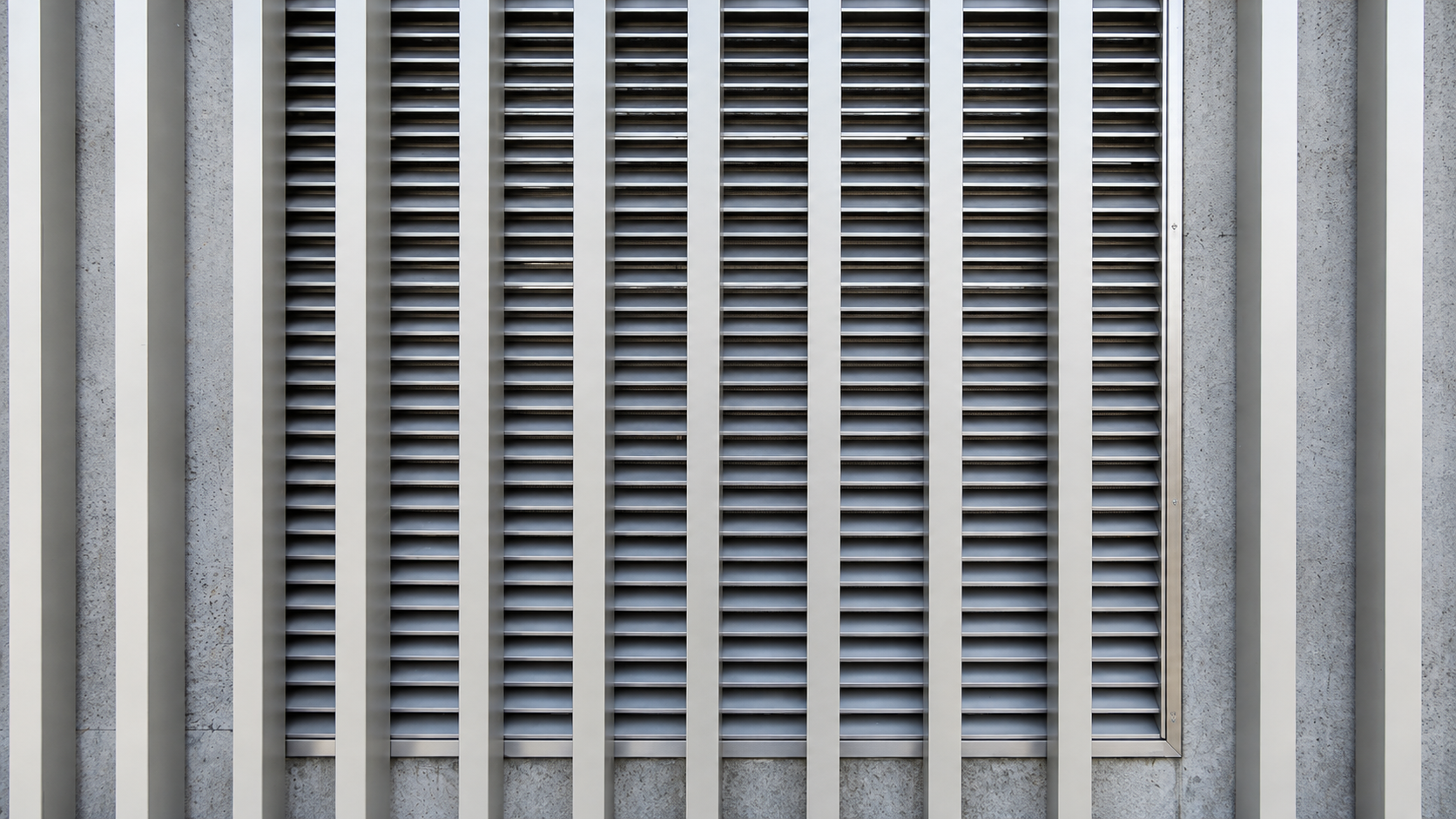 Vertical architectural fins installed in front of horizontal ventilation louvers.