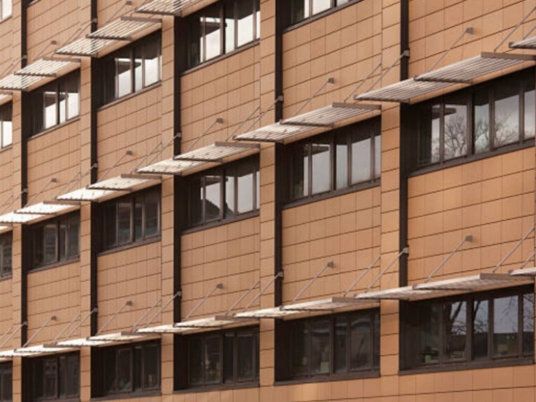 Rows of windows fitted with airfoil-sunshades on a modern façade.