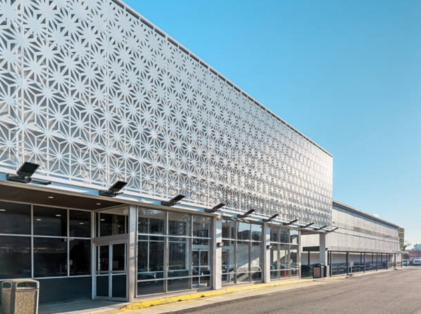 Commercial building exterior featuring architectural metal cladding with decorative perforated panels and a modern facade design.